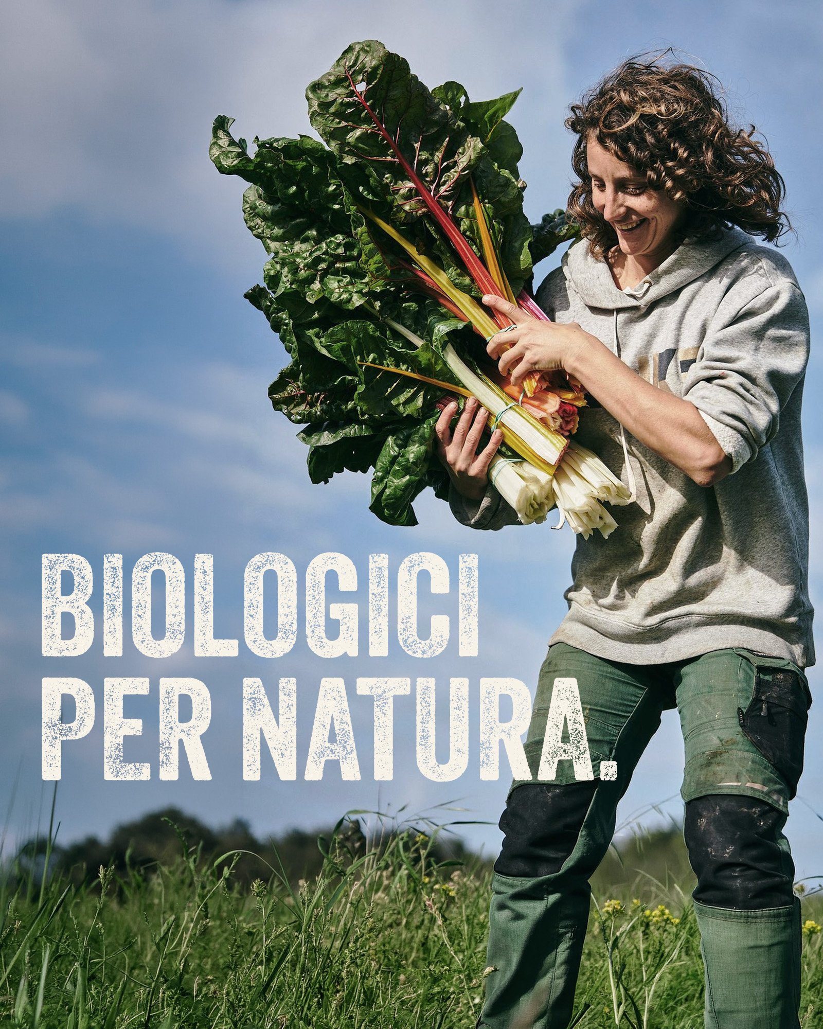 Donna in un campo che tiene un grande mazzo di bietole con la scritta biologici per natura