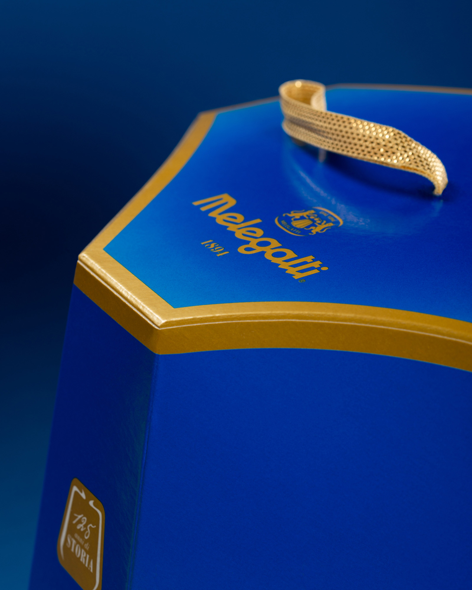 Dettaglio della confezione blu e oro melegatti con logo e manico dorato su sfondo blu